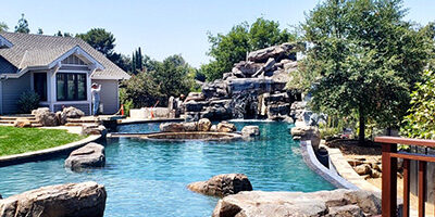 A California backyard with custom artificial rock work and a pool by Matrix Concrete Artisans.